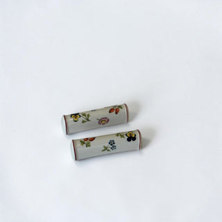 Her Good Eye set of two cylindrical porcelain knife rests with hand-painted vintage floral motifs and red trim.