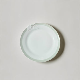 Her Good Eye white porcelain dinner plate with a sage green rim and embossed leaf detail on a neutral background.
