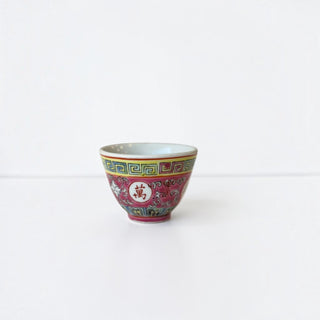 Her Good Eye hand-painted porcelain tea cup featuring magenta, yellow, and teal floral motifs and a calligraphic symbol.