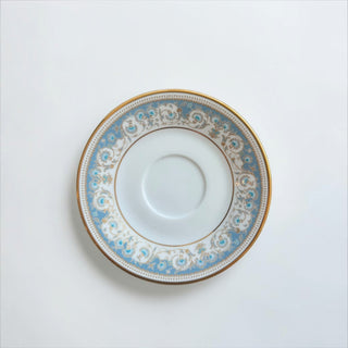 Her Good Eye fine porcelain tea saucer with blue and gold floral border and elegant gold-trimmed edge.