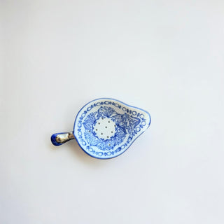 Her Good Eye white porcelain tea strainer with hand-painted blue floral patterns and ergonomic handle.