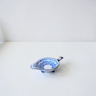 Her Good Eye white porcelain tea strainer with hand-painted blue floral motif and ergonomic handle.