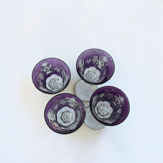 Her Good Eye set of four vintage-inspired purple crystal wine glasses with intricate hand-cut floral and starburst motifs.