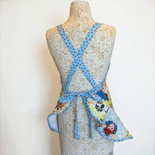 Her Good Eye vintage style quilted apron with Raggedy Ann and Andy print and blue floral cross-back straps on a mannequin