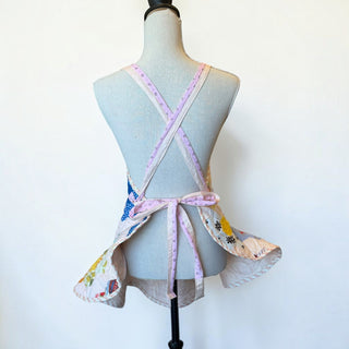 Back view of a Her Good Eye handmade quilted patchwork apron with floral and gingham hexagon motifs on a mannequin.