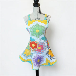 Her Good Eye handmade quilted patchwork apron with vibrant floral hexagon patterns in yellow, green, orange, and purple.