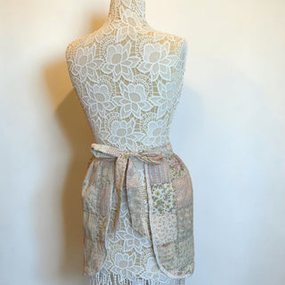 Her Good Eye vintage quilted patchwork waist apron in pastel floral and gingham patterns with fringe trim on a mannequin