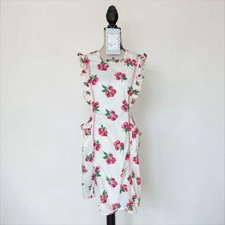 Her Good Eye white cotton apron with all-over raspberry print, ruffled trim, and red pinstripe pockets.