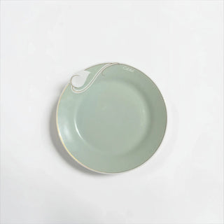 Her Good Eye sage green ceramic serving plate with a sculptural rim detail and delicate gold-toned trim.
