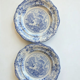 Her Good Eye blue and white ceramic dinner plates with scalloped edges and intricate pastoral transferware scenes.