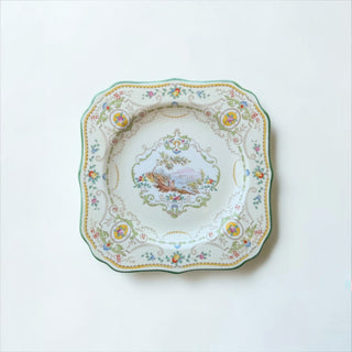Her Good Eye scalloped edge porcelain plate with pastoral scene, bird, mountains, and green trim.