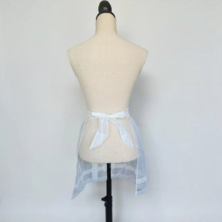 Her Good Eye sheer white organza half apron with lace hem detail tied at the waist on a mannequin