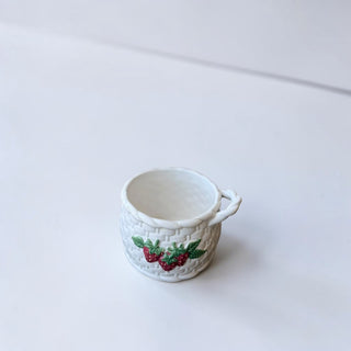 Her Good Eye white ceramic mug designed like a basket with embossed strawberries and green leaves.