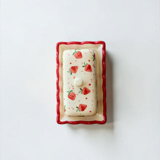 Her Good Eye hand-painted ceramic butter dish with a strawberry pattern, creamy white base, and scalloped red trim.