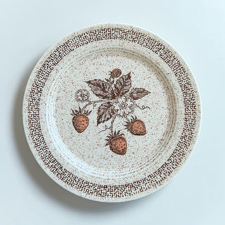 Her Good Eye strawberry pattern ceramic dinner plate with brown geometric rim and speckled off-white base.