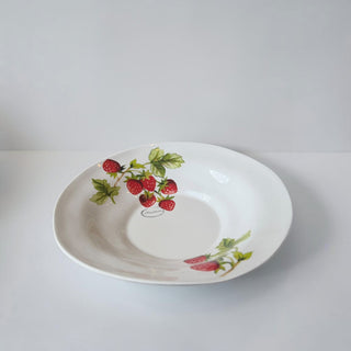 Her Good Eye white ceramic serving bowl with a hand-painted strawberry pattern and green leaves.