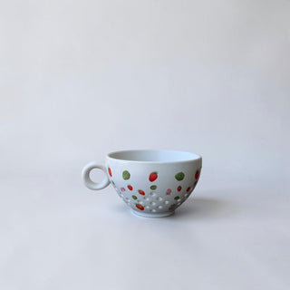 Her Good Eye white ceramic tea cup with a strawberry and leaf pattern and textured dimples.