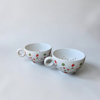 Her Good Eye white ceramic tea cup with strawberry and leaf pattern and dimpled base.