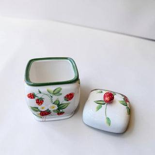 Her Good Eye strawberry patterned ceramic trinket dish with lid, featuring hand-painted red strawberries, white blossoms, and green leaves on a white background.