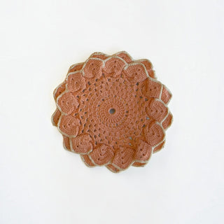 Her Good Eye handmade terracotta crochet table doily with a beige scalloped edge and intricate floral pattern.