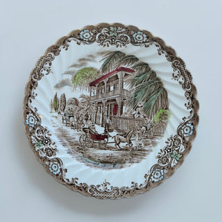 Her Good Eye Victorian era decorative plate with horse-drawn carriages and colonial house scene. Sepia tones, blue floral border.