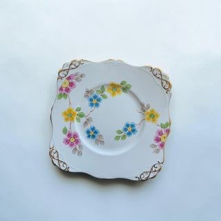 Her Good Eye vintage floral square dessert plate with pink, yellow, and blue flowers and gold trim.