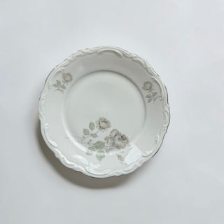 Her Good Eye vintage porcelain dinner plate with grey floral motifs, scalloped embossed rim, and silver-toned edge.