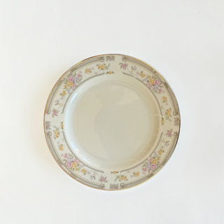 Her Good Eye vintage porcelain dinner plate with pastel floral pattern, grey scrollwork, and gold-tone rim.