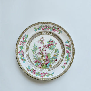 Her Good Eye vintage porcelain plate with pink peony floral motif, green foliage, and gold geometric border.