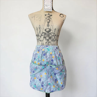 Her Good Eye vintage half apron with abstract brushstrokes and polka dots in blue, purple, yellow, and green trim. Tie waist and two pockets.