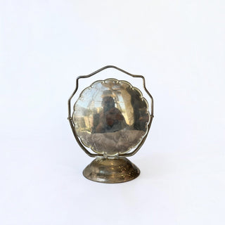Her Good Eye vintage-inspired ornate metal tabletop swivel mirror with an aged metallic finish on a pedestal base.
