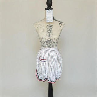 Her Good Eye vintage style white half apron with red and navy polka dots, ruffled hem, and rickrack trim on mannequin.
