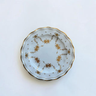Her Good Eye vintage white porcelain plate with scalloped edges and intricate gold floral motifs and gold rim trim.
