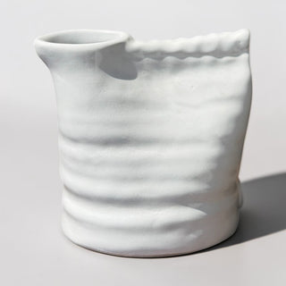 Her Good Eye white ceramic vase with a unique crumpled bag shape and glossy finish, featuring wave-like indentations.