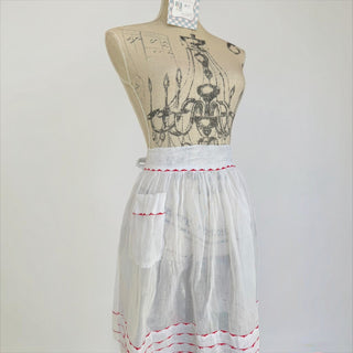 Her Good Eye white cotton half apron with red embroidery on hem and pocket. Vintage style, adjustable ties.
