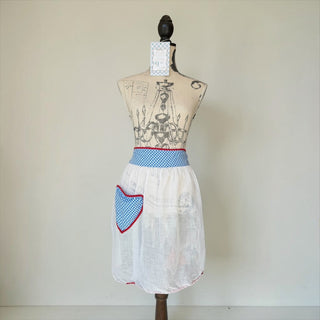 Her Good Eye white linen half apron with blue gingham pocket and waistband, trimmed in red. Lightweight and sheer.