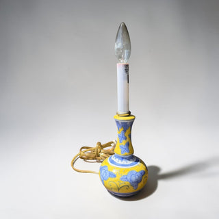 Her Good Eye yellow ceramic table lamp with blue floral accents and curved silhouette.