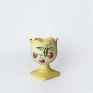 Her Good Eye yellow ceramic egg cup with hand-painted strawberry motif and scalloped rim on a pedestal base.
